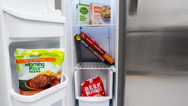 A close-up of the Frigidaire FFSS2315TS side-by-side refrigerator's freezer compartment, underneath its ice-maker, which takes up the top quarter of the total space.