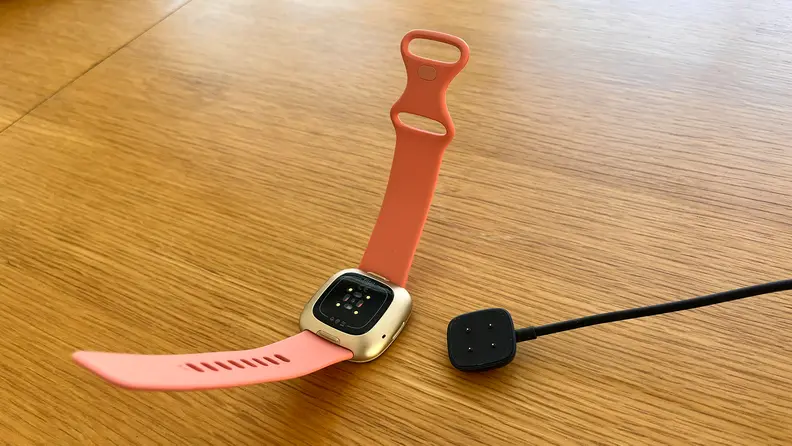 A smartwatch next to its magnetic charger
