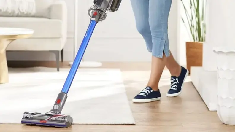 woman vacuuming white rug with Dyson vacuum