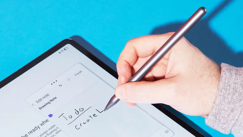 Close-up of a hand using the tablet's pen to write.