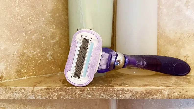 The Gillette Venus Extra Smooth Swirl laying on a shower shelf with body wash behind it.