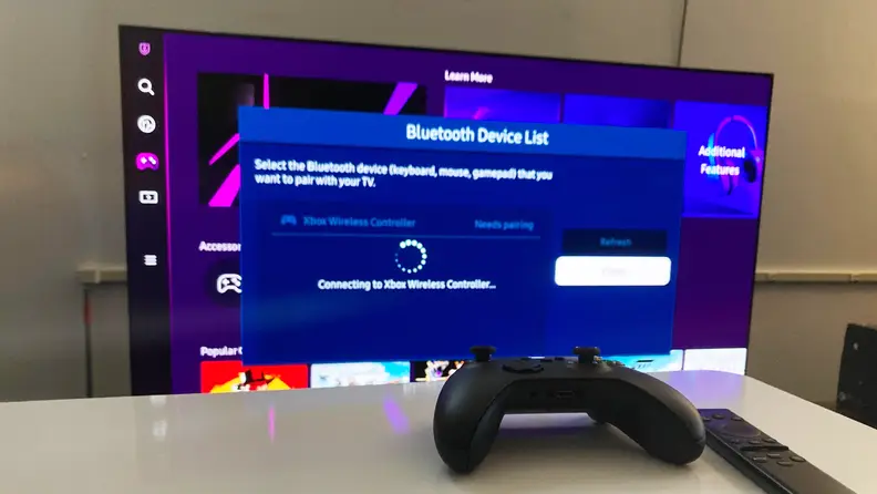 An Xbox Series X wireless controller in front of a Samsung TV, with the TV displaying a message about the status of its Bluetooth connection to said controller