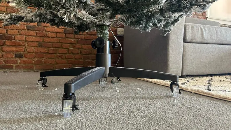 A black artificial Christmas tree stand with wheels.