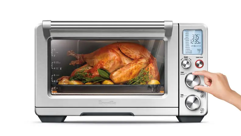 Person adjusting the temperature on the Breville Smart Oven as it's roasting a whole chicken