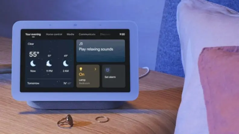 the google nest hub second gen on a bedside table in dim light