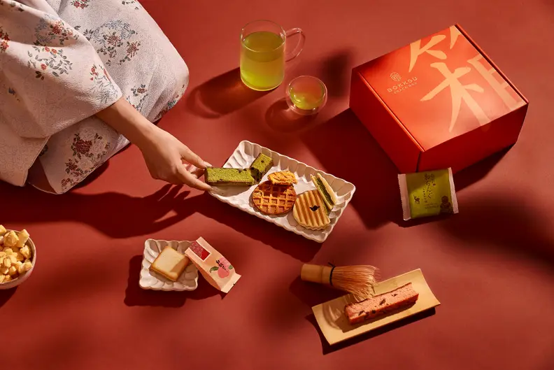 Woman's hand among a spread of Bokksu offerings