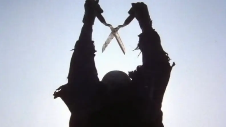 A man in a shadow, holding a pair of clippers, in a scene from "The Burning."