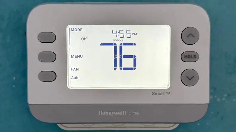A smart thermostat against a blue wall