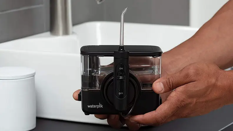 A person fills a waterpik.