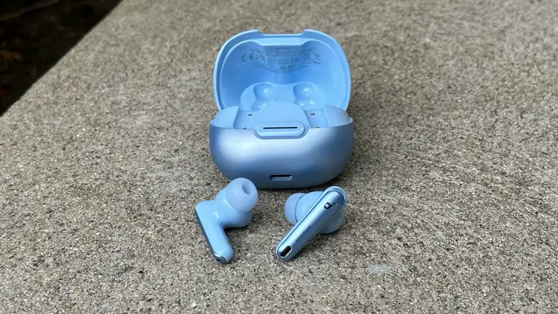 The Anker Soundcore Liberty 4 NC earbuds and their open case sitting on a concrete surface.