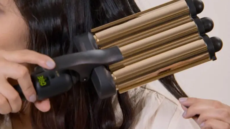 Woman with black hair uses Hot Tools Pro Artist 24K Gold 3 Barrel Waver