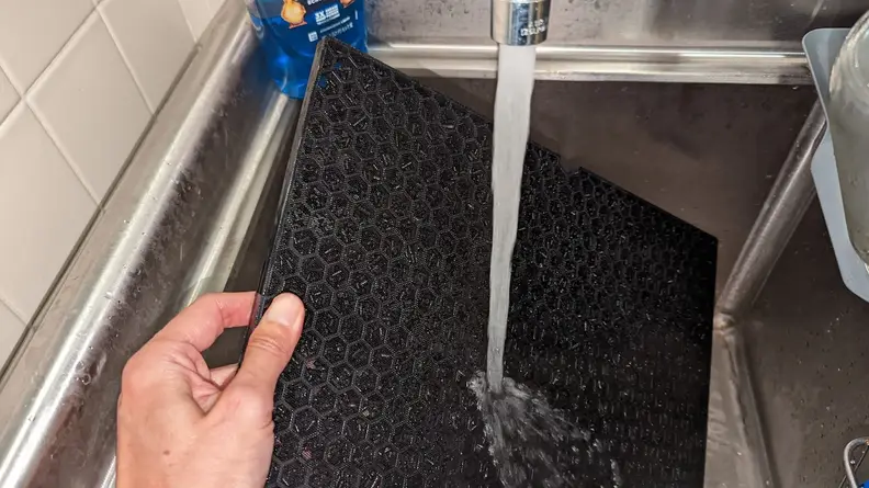 A washable carbon filter being rinsed without causing damage.