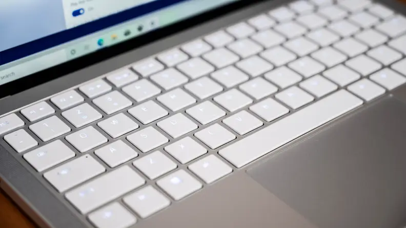 The laptop's keyboard is shown, white keys on a silver chassis.