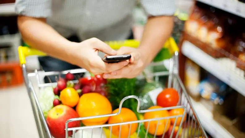 A person on their phone while grocery shopping.