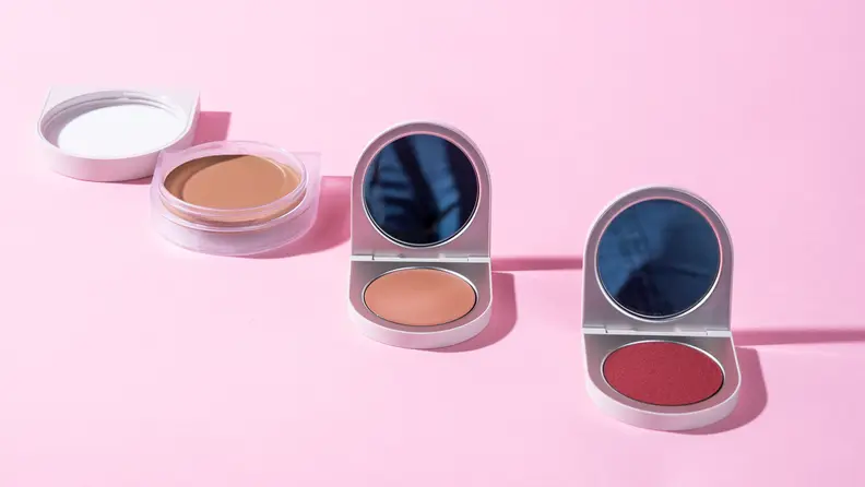 Compacts of Rose Inc. cream foundation, highlighter and blush.