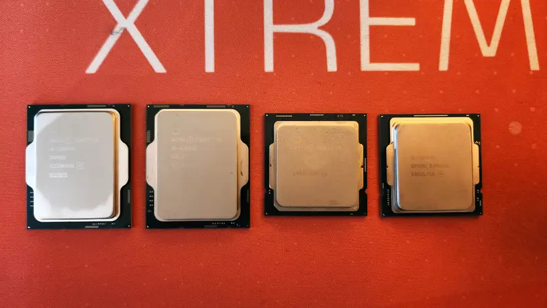Four desktop computer processors arranged in a line on top of an orange mat.