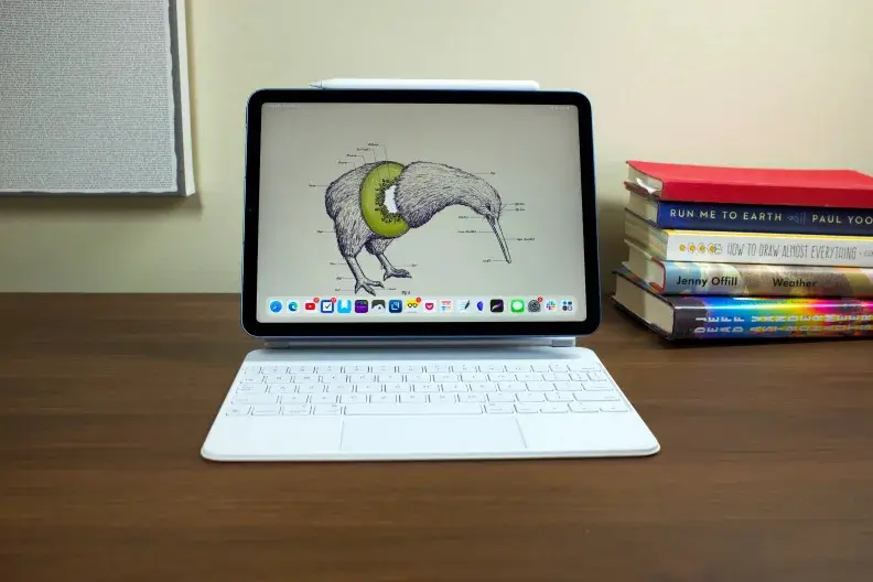 Apple's iPad Air, docked into the Magic Keyboard (white), with a wallpaper of a kiwi bird showing on the display.