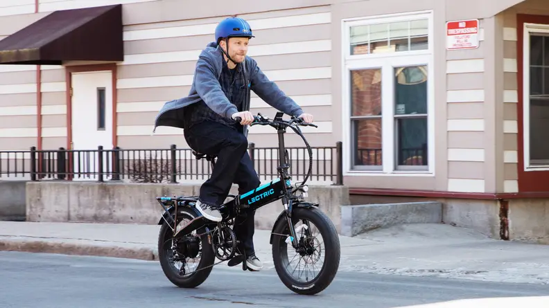 A tester from Reviewed rides an e-bike down the street