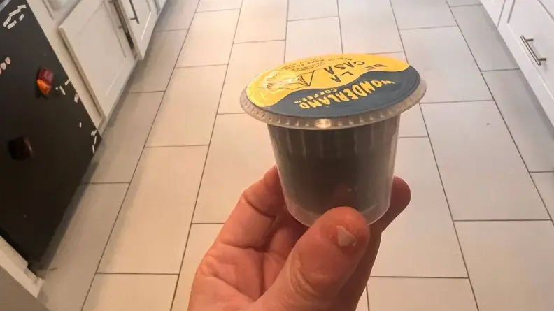 Person holding a Bruvi coffee pod in their fingers.