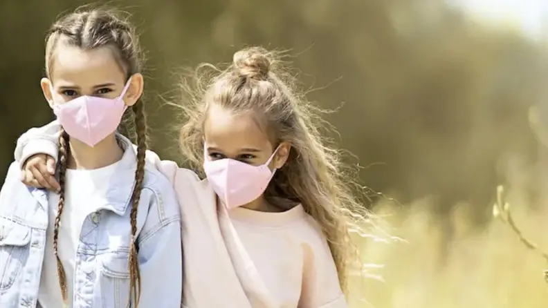 Two girls wearing face masks outside.