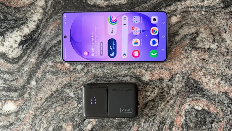 iPhone and INIU Pocket Rocket 50 portable charger sitting on a dark grey marble counter.