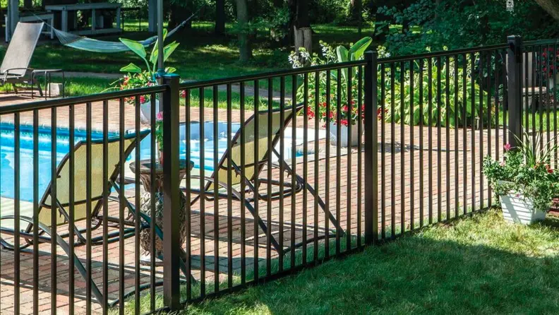 A metal fence wraps around a backyard pool area.