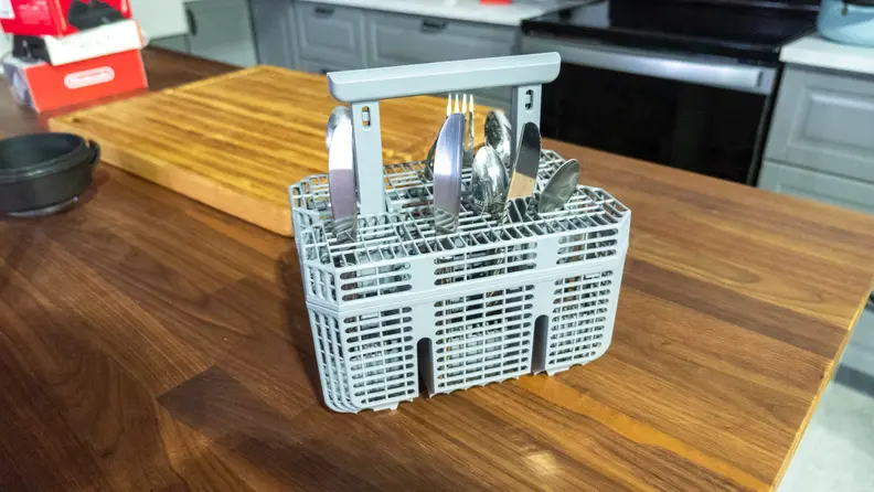 A shot of the Hisense HUI6220XCUS dishwasher's cutlery basket sitting out on a wooden countertop.