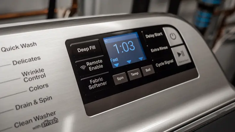 A close-up of a black touchpad, located off to the right of the Maytag MVW7230HW washer's back panel.
