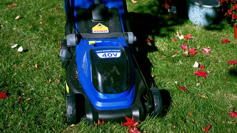 The front of A blue lawn mower sits in a grassy spot