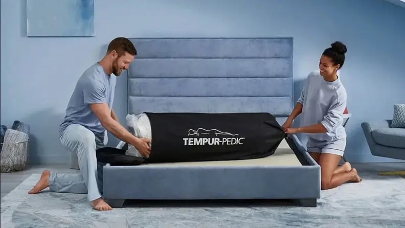 a couple set up a Tempur-Pedic on a bed frame