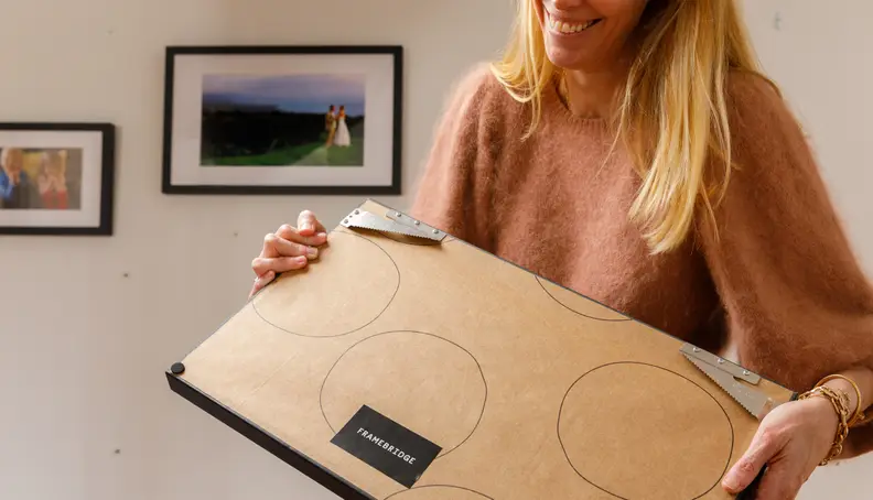 A woman holds up a framed photo