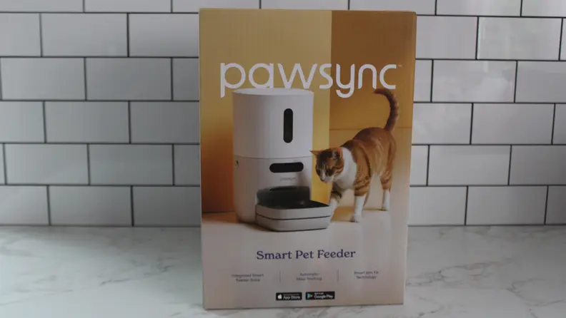 The box for the PawSync Smart Pet Feeder on a marble countertop in front of a tile wall.
