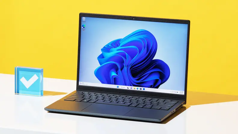 The Dell Inspiron 14 Plus, open, on a desk with a yellow background.