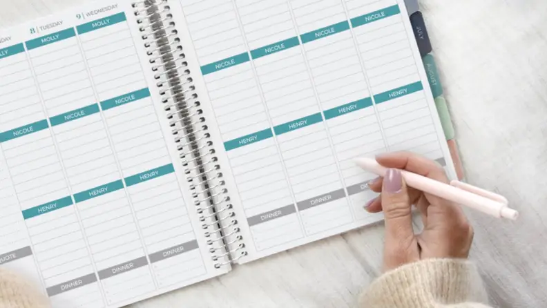 A person writes in a daily planner.