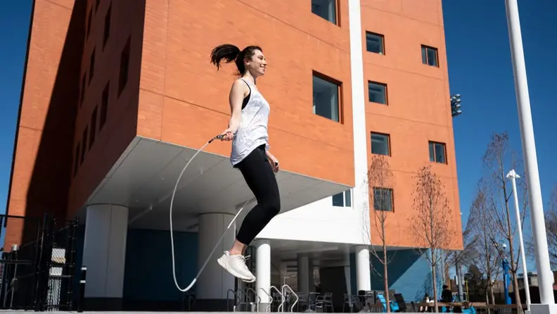 A woman jumping with a jump rope outside.