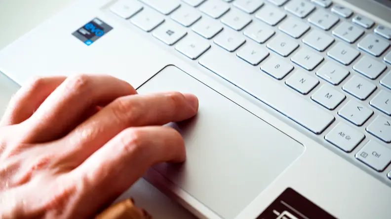 A close up of a person's fingers touching a trackpad on a laptop.