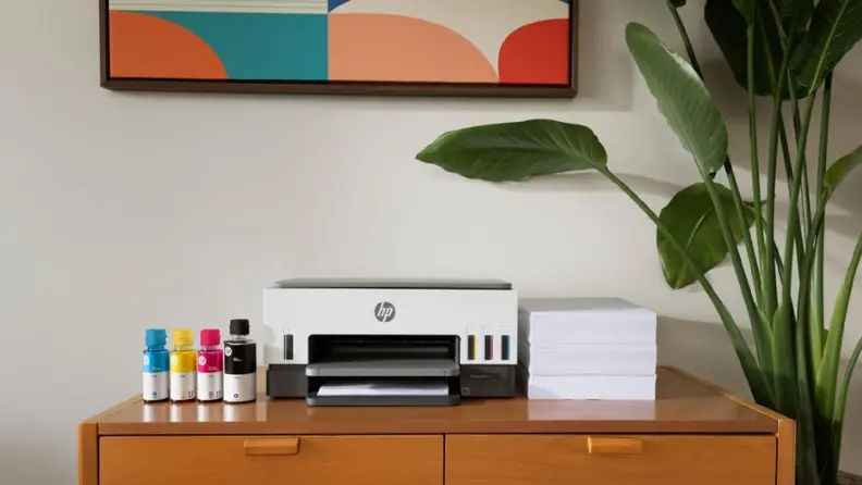 An HP Cartridge-free printer is displayed on a wooden cabinet alongside colorful ink refill bottles and a stack of paper.