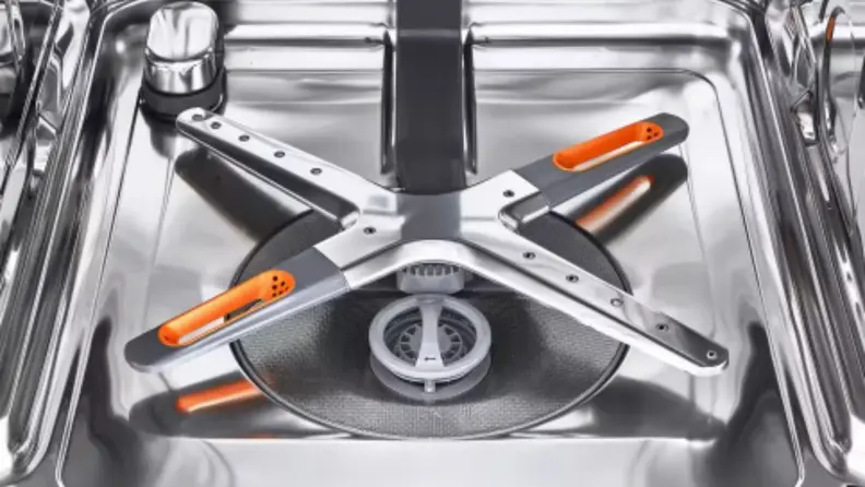 A spray arm is dry inside a stainless steel dishwasher