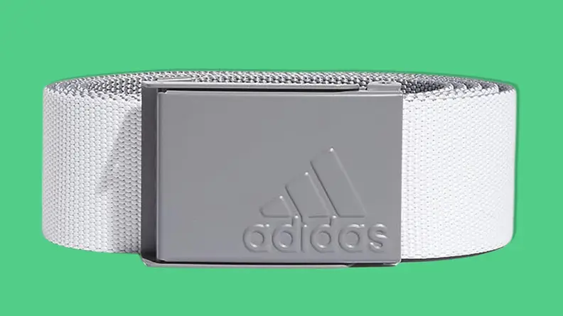 Adidas Golf Reversible Web Belt on green background.