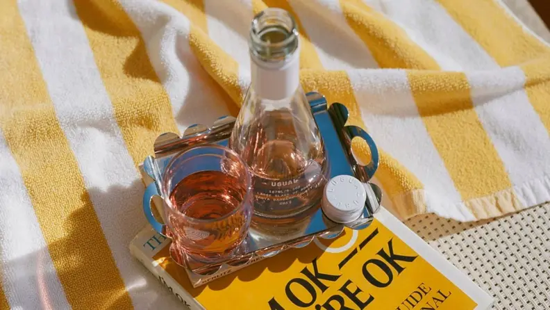 A picnic blanket with a bottle and glass of Usual Wines rosé.