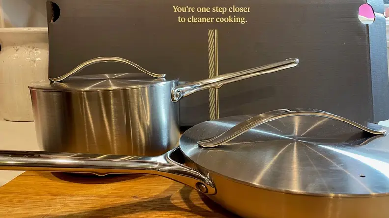 One stainless steel pot and frying pan sitting on top of wooden surface.