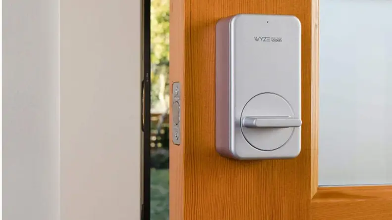 Silver smart lock attached to cracked door in home.