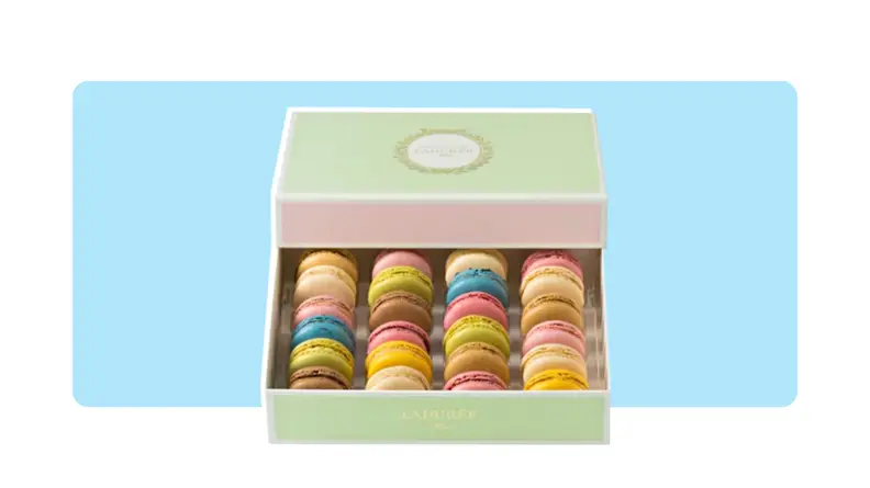 A box of multi-colored macarons in front of a background.