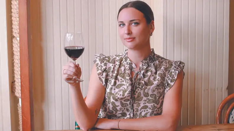 Photo of Marissa Mullen holding a glass of red wine.