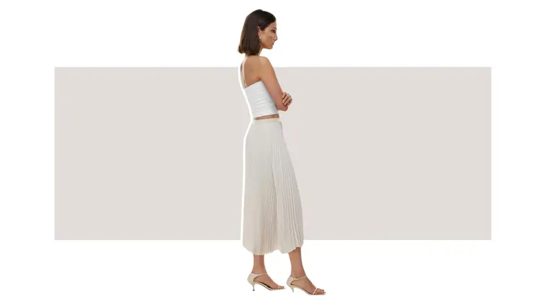 A model wearing a white pleated skirt with an asymmetrical hem.