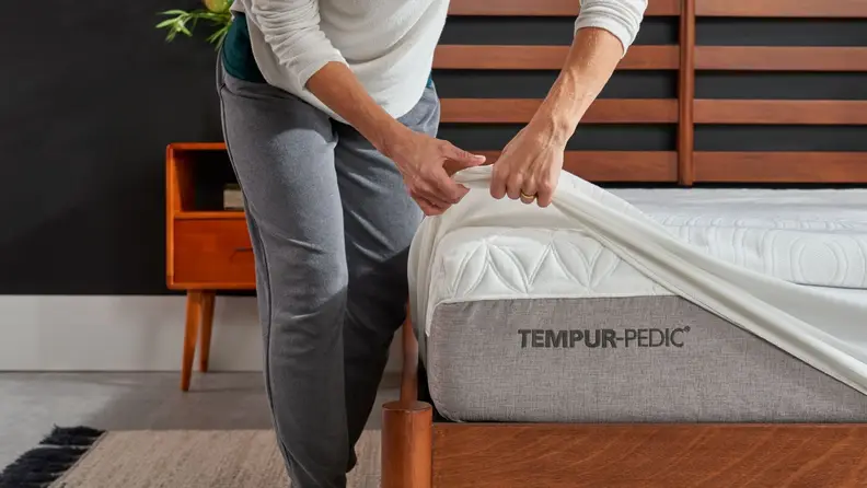 A man puts a Tempur-Pedic mattress protector on his Tempur-Pedic mattress