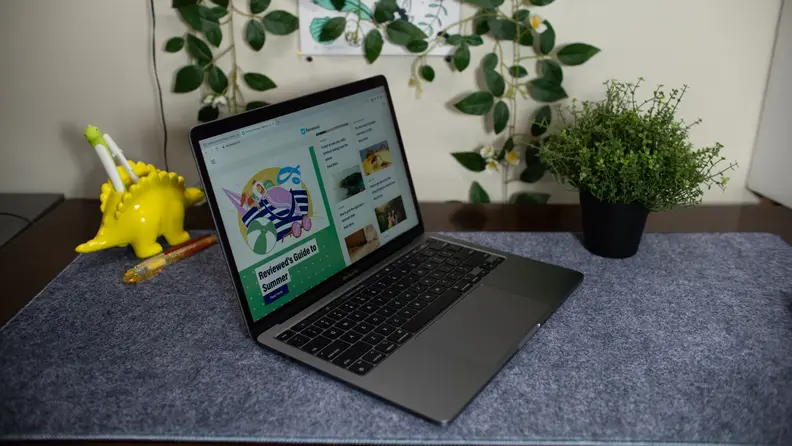 A dinosaur pencil holder sits behind the laptop.