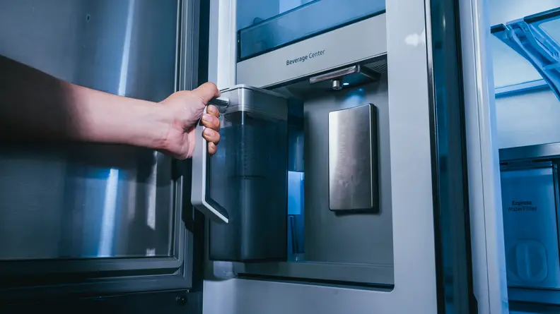 A person pulls out a water pitcher from a refrigerator