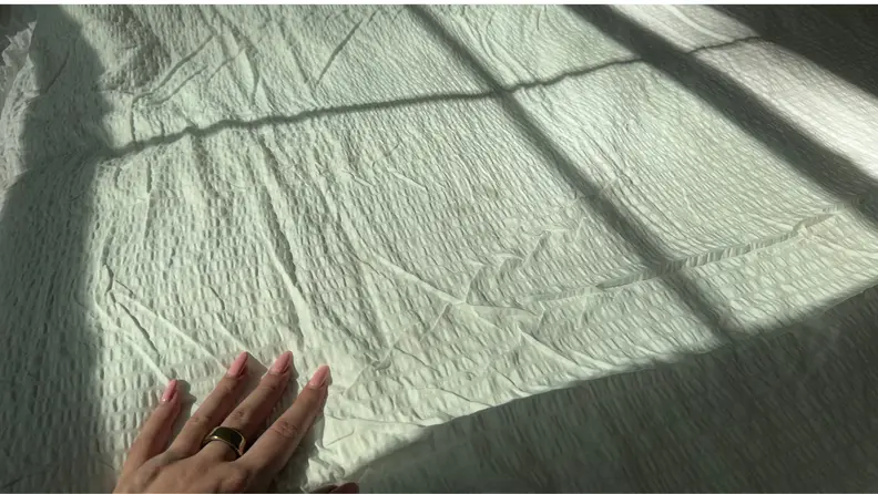A hand on a blanket on a bed
