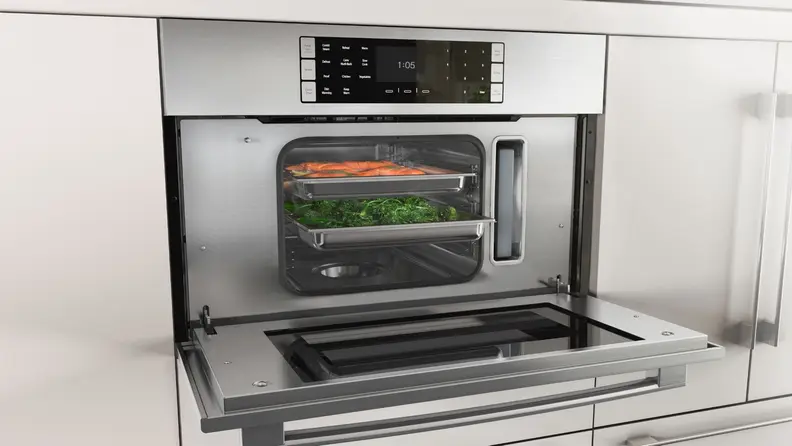 A photo of a steam oven with its door open and food steaming inside.